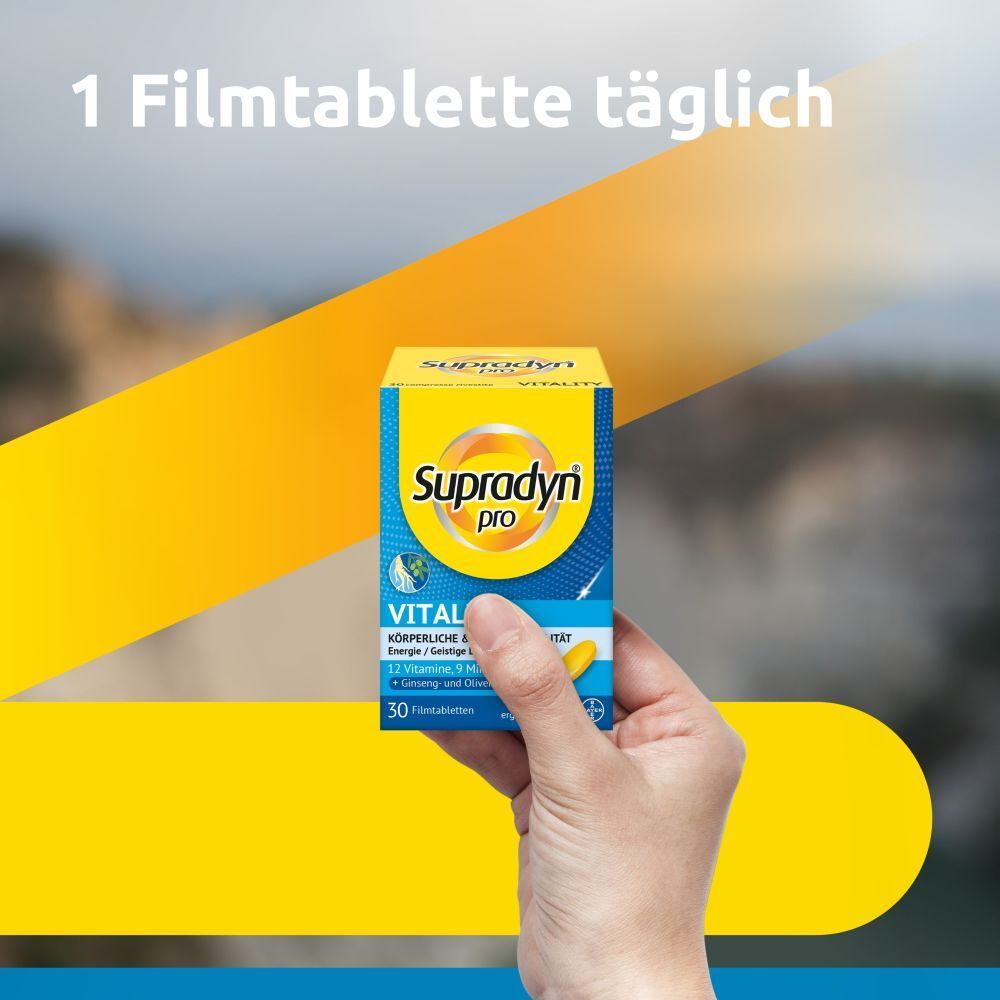 Main tenant une boîte de Supradyn pro Vitality. Inscription: 30 comprimés pelliculés. Fond jaune avec éléments jaunes et bleus.