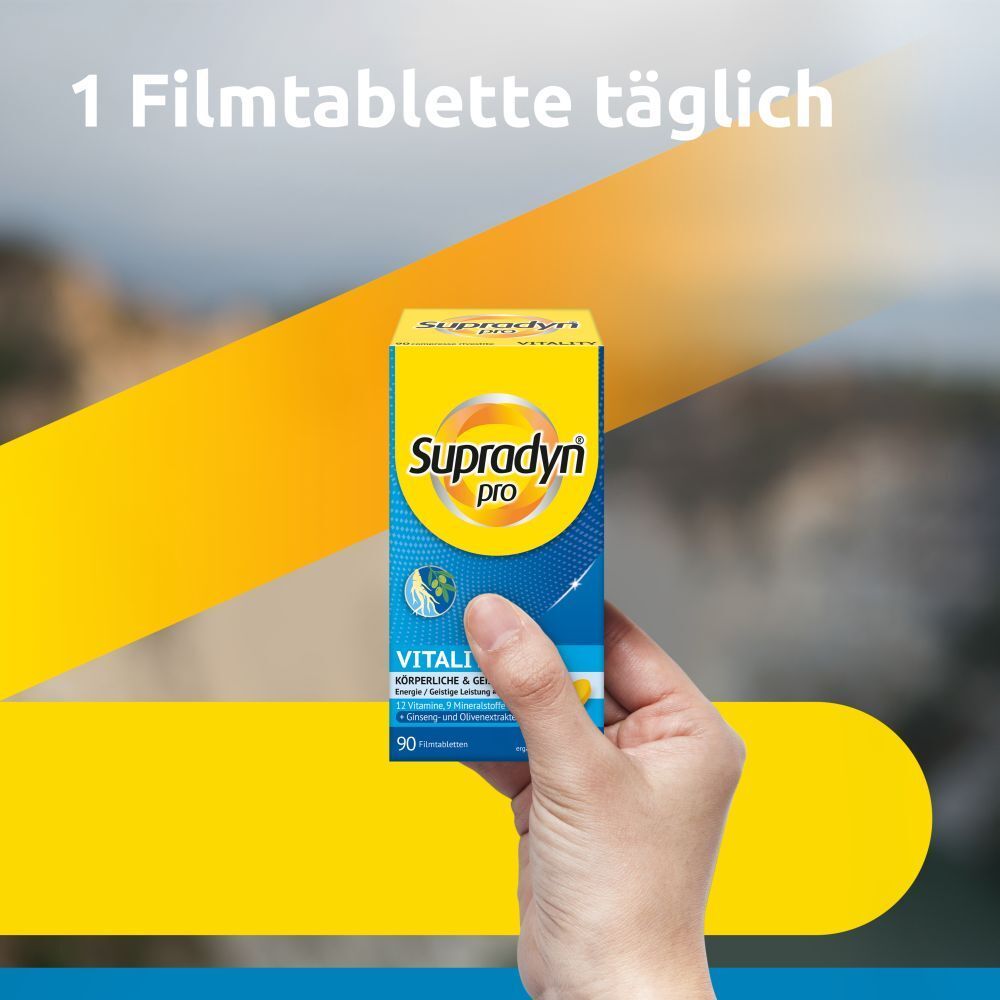 Hand hält eine Schachtel Supradyn pro Vitality. Aufschrift: 90 Filmtabletten. Gelber und blauer Hintergrund.
