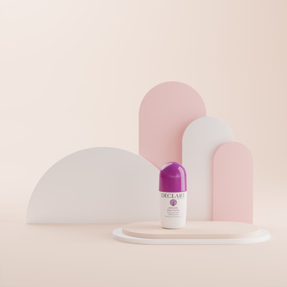 Deo Forte Roll-on auf Podest. Hintergrund: abstrakte Formen in Rosa und Weiß. Lila Kappe sichtbar.