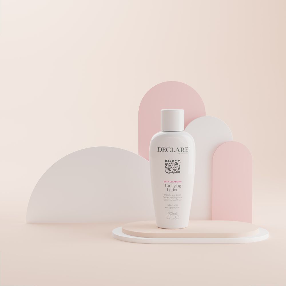 Weiße Flasche mit Deckel auf einem Podest. Aufschrift: DECLARÉ, Logo, Toning Lotion. Hintergrund: Beige, Rosa und Weiß.