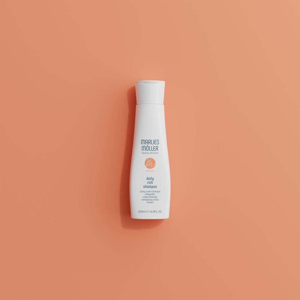 Weiße Flasche Marlies Möller Daily Rich Shampoo auf orangefarbenem Hintergrund. Orangefarbenes Logo. Flasche mit weißem Deckel.