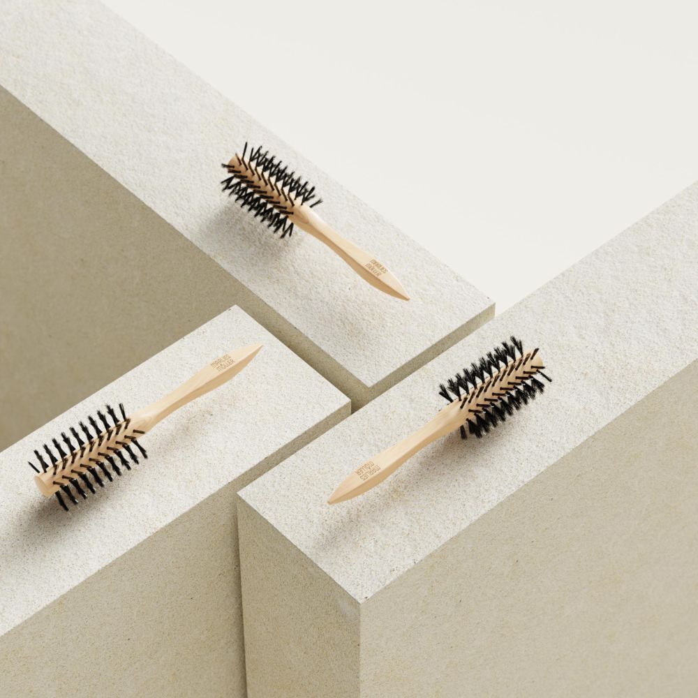 Drei runde Haarbürsten auf weißen Blöcken. Holzgriff, schwarze Borsten. 