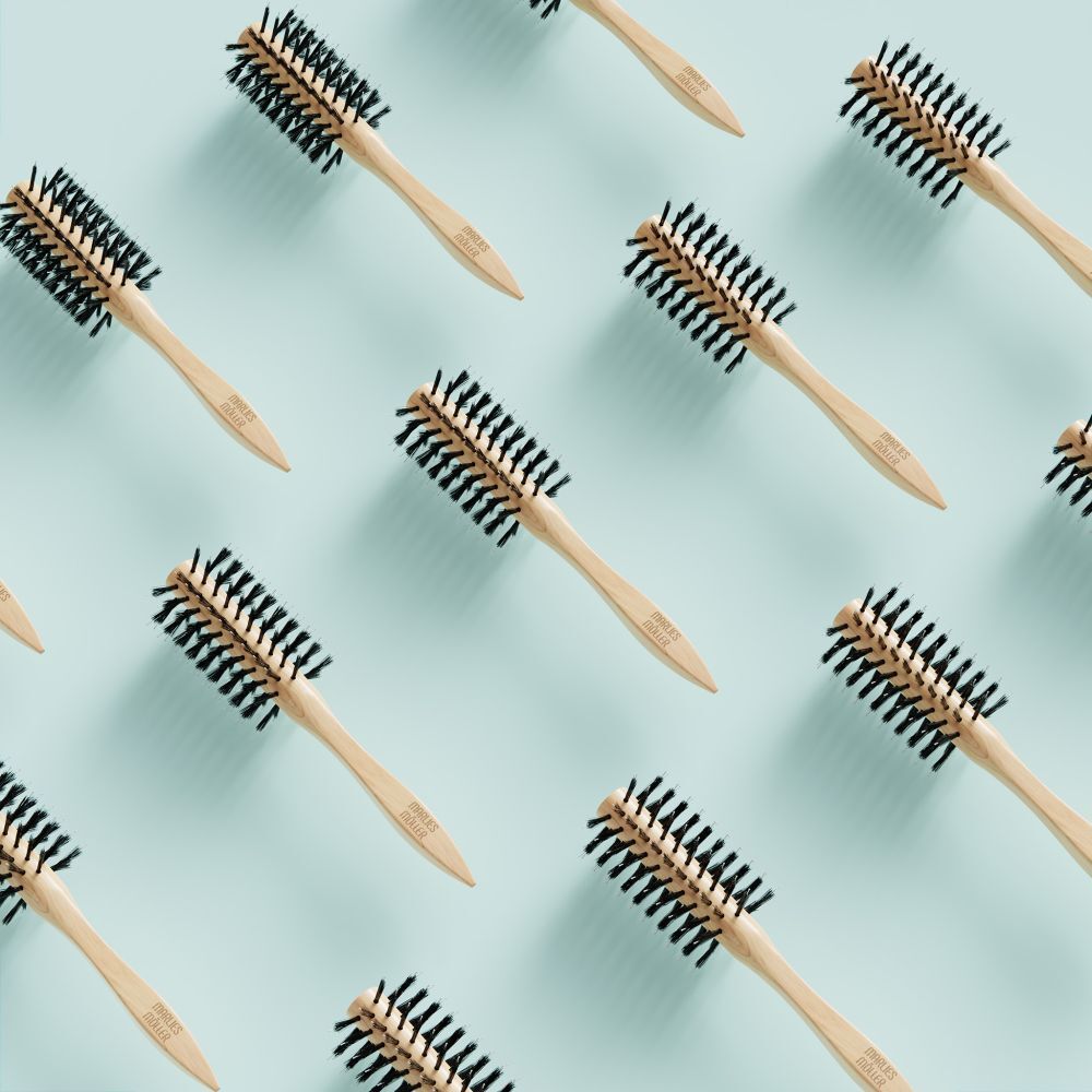 Muster aus runden Haarbürsten auf hellblauem Hintergrund. Holzgriff, schwarze Borsten.