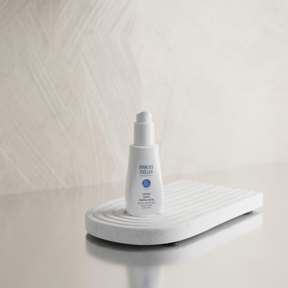 Weißes Spray von Marlies Möller auf weißem Podest. Text: Volume Boost Styling Spray.