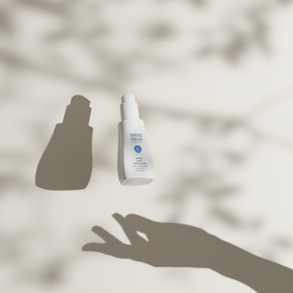Weißes Spray von Marlies Möller, Schatten einer Hand. Text: Volume Boost Styling Spray.