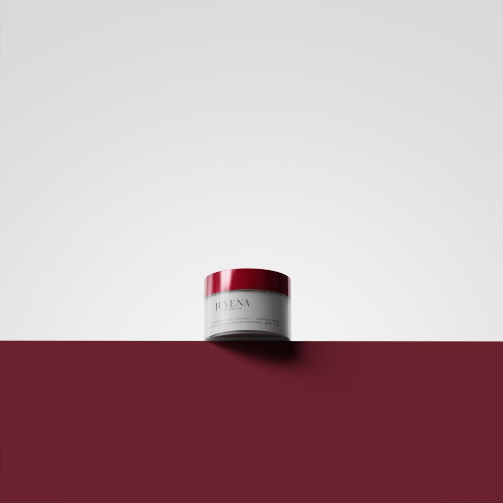 Creme-Dose mit rotem Deckel auf rotem Untergrund. Aufschrift: Juvena. Produktname nicht lesbar.