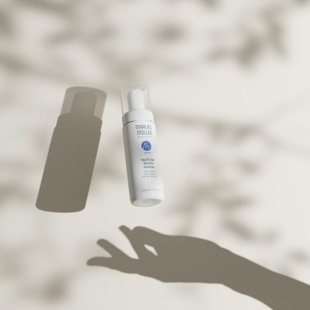 Weiße Flasche mit Sprühkopf. Aufschrift: Marlies Möller, beauty haircare, Volume, Liquid Hair Keratin Mousse. Mit Schatten.