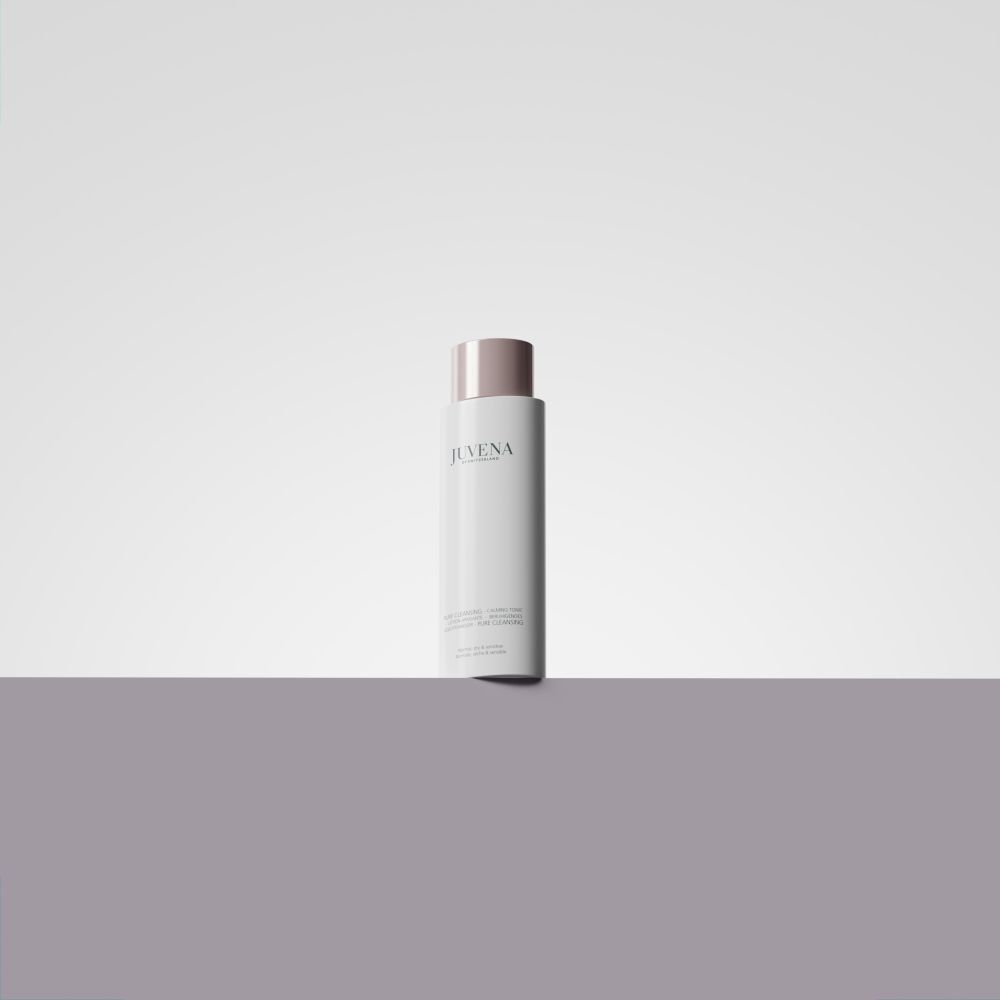 Weißes Fläschchen mit rosafarbenem Deckel. Auf einer grauen Fläche platziert.