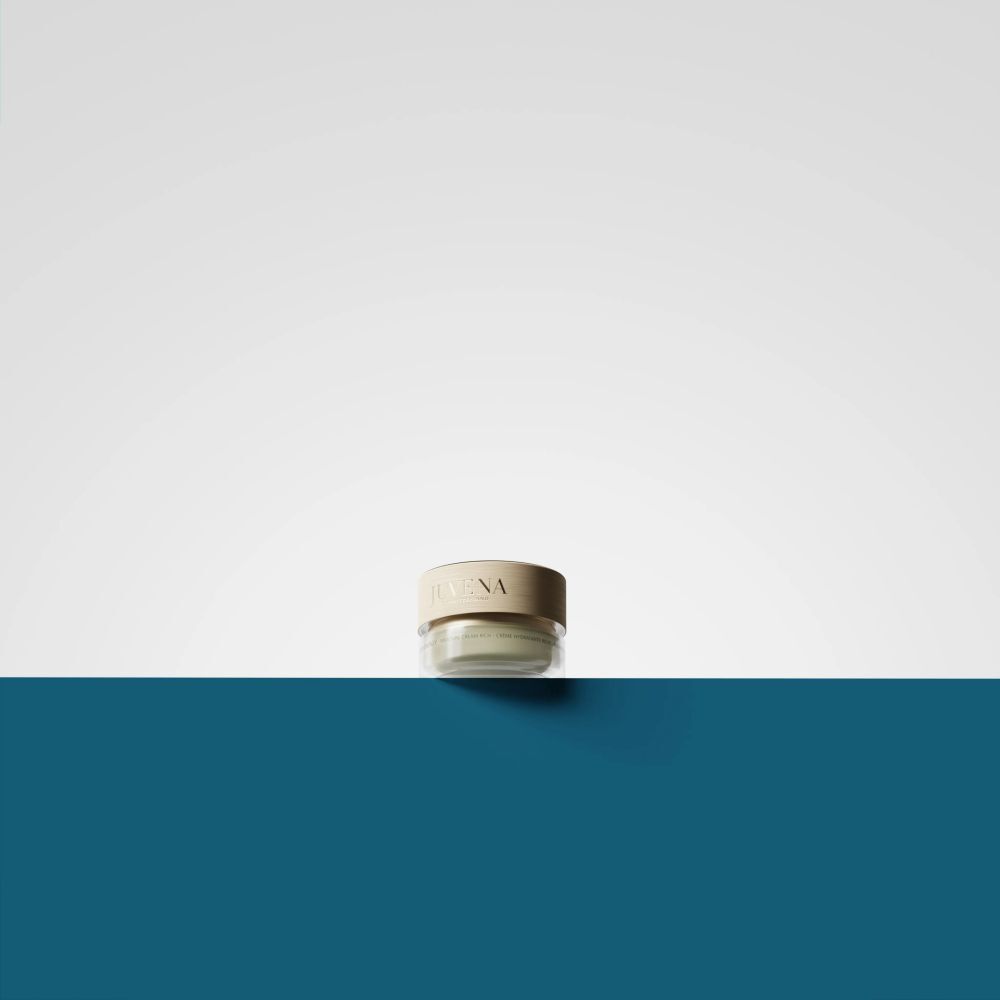 Kleiner Creme-Tiegel mit goldfarbenem Deckel. Aufschrift: Juvena. Auf blau-weißem Hintergrund.