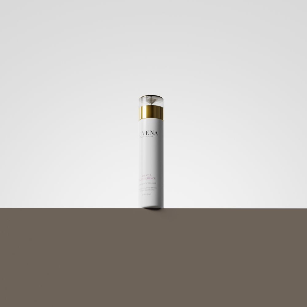 Weißer Flakon mit goldener Kappe. Aufschrift: Juvena, Miracle Boost Essence. Auf braunem Untergrund.