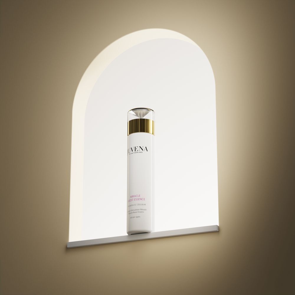 Weißer Flakon mit goldener Kappe. Aufschrift: Juvena, Miracle Boost Essence. In einer Nische.