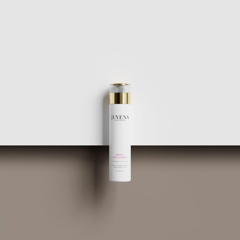 Weißer Flakon mit goldener Kappe. Aufschrift: Juvena, Miracle Boost Essence. Auf weißem Untergrund.
