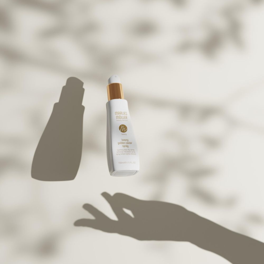 Spray mit goldenem Verschluss schwebt. Schatten einer Hand und Blätter. Aufschrift: Marlies Möller, Luxury Golden Caviar Spray.