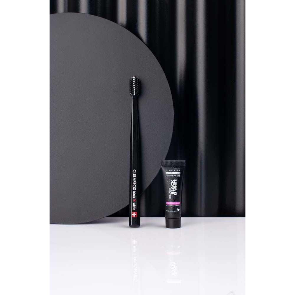 CURAPROX Schwarz ist Weiß Light-Pack. Schwarze Zahnbürste und Zahnpasta. Hintergrund mit Kreisen. Marke sichtbar.