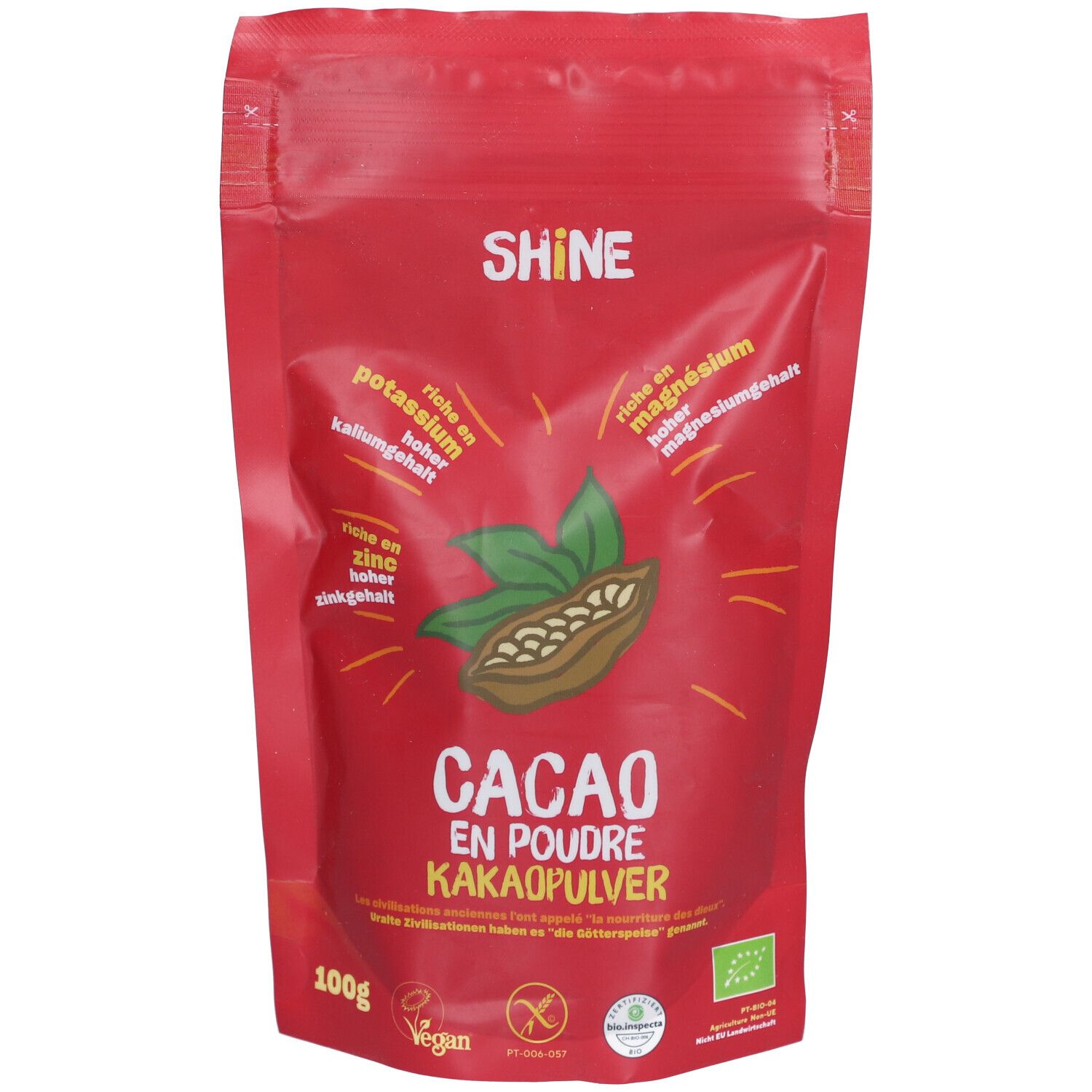 Rote Tüte mit SHINE Kakaopulver. Aufschrift "CACAO EN POUDRE KAKAOPULVER". Enthält Blätter und Kakaobohne.