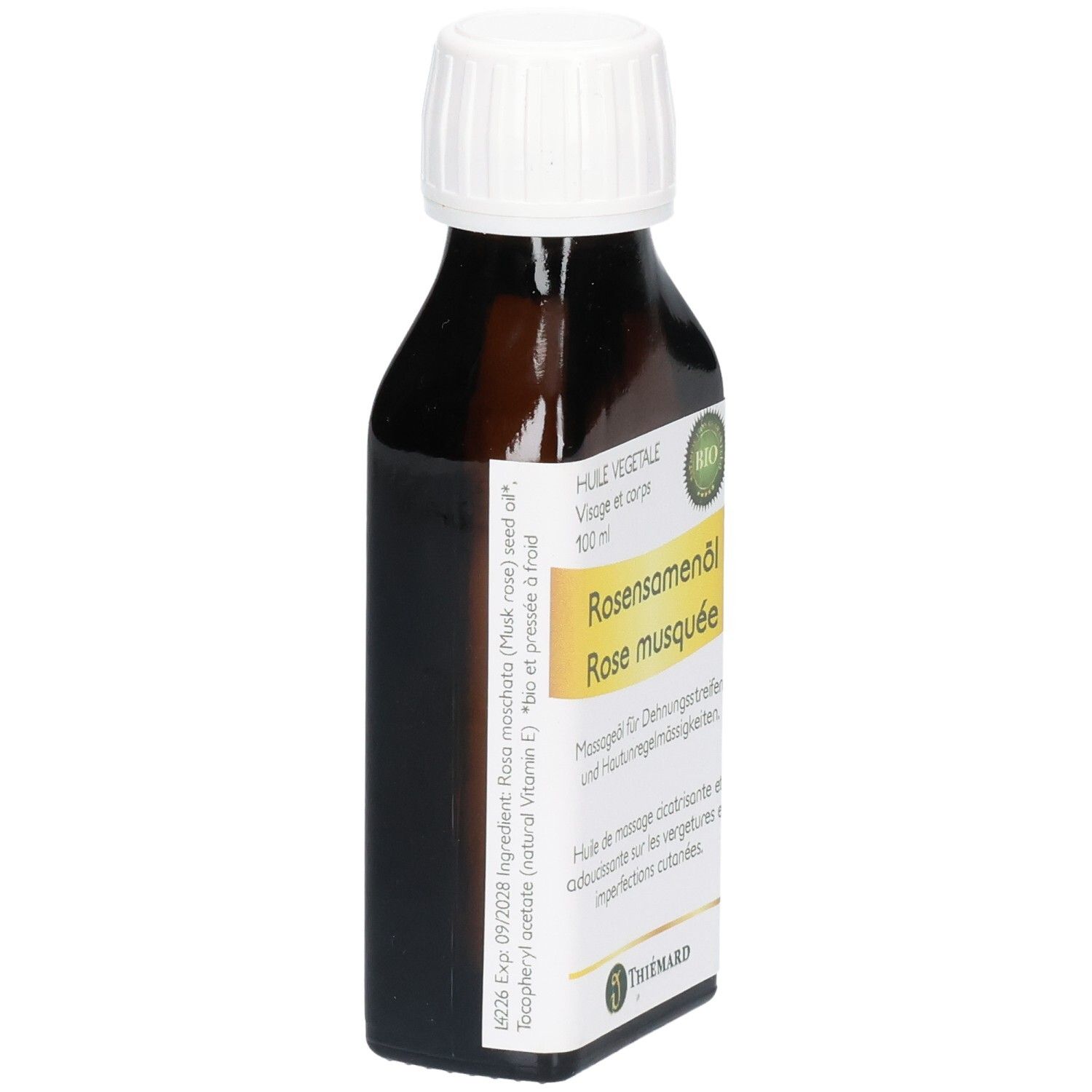 Braune Glasflasche mit weißem Schraubverschluss, gefüllt mit Rosenöl. Etikett mit Produktinformationen und Markennamen.