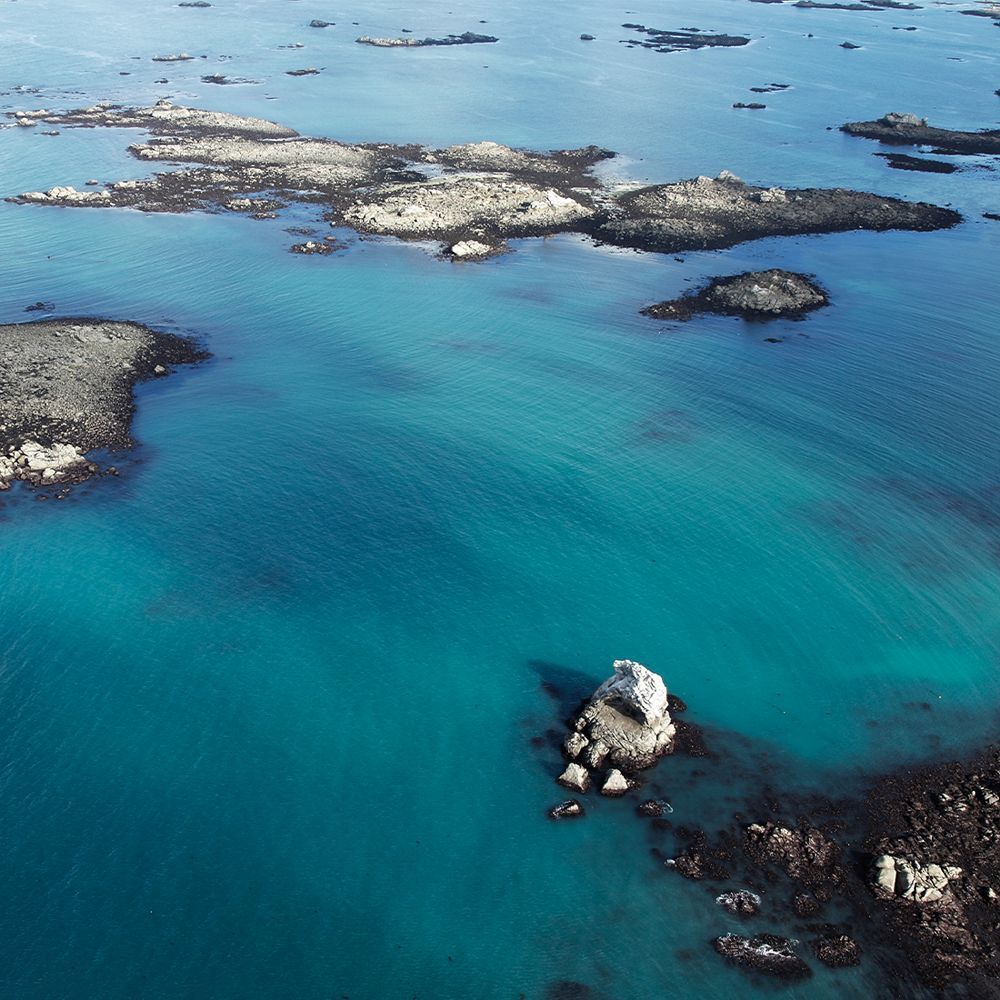 Luftaufnahme von blauem Wasser mit Felsen und Inseln.