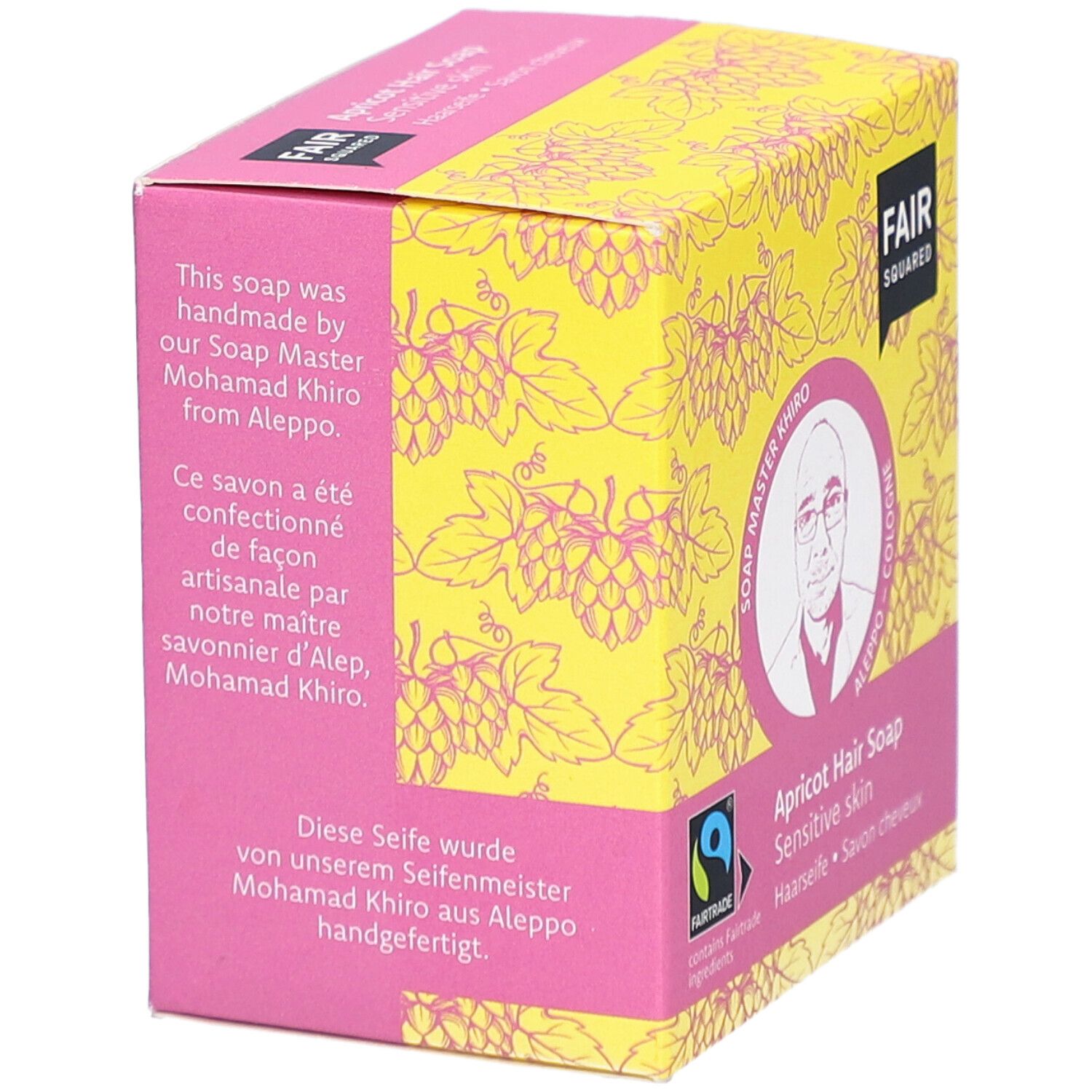 Verpackung der Haarseife. Text: handgefertigt von Soap Master Khiro aus Aleppo. FAIRTRADE-Siegel. Gelber Hintergrund mit Traubenmuster.