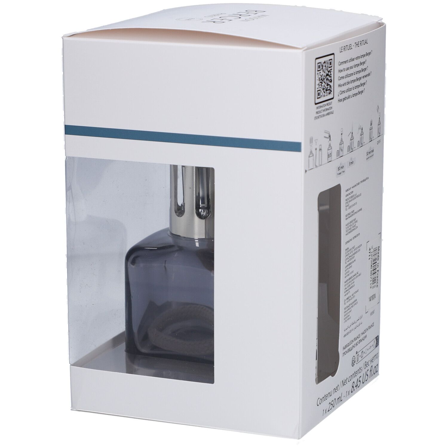 Duftlampe in Verpackung. Graue, eckige Lampe mit Docht. Verpackung weiß mit transparentem Fenster.