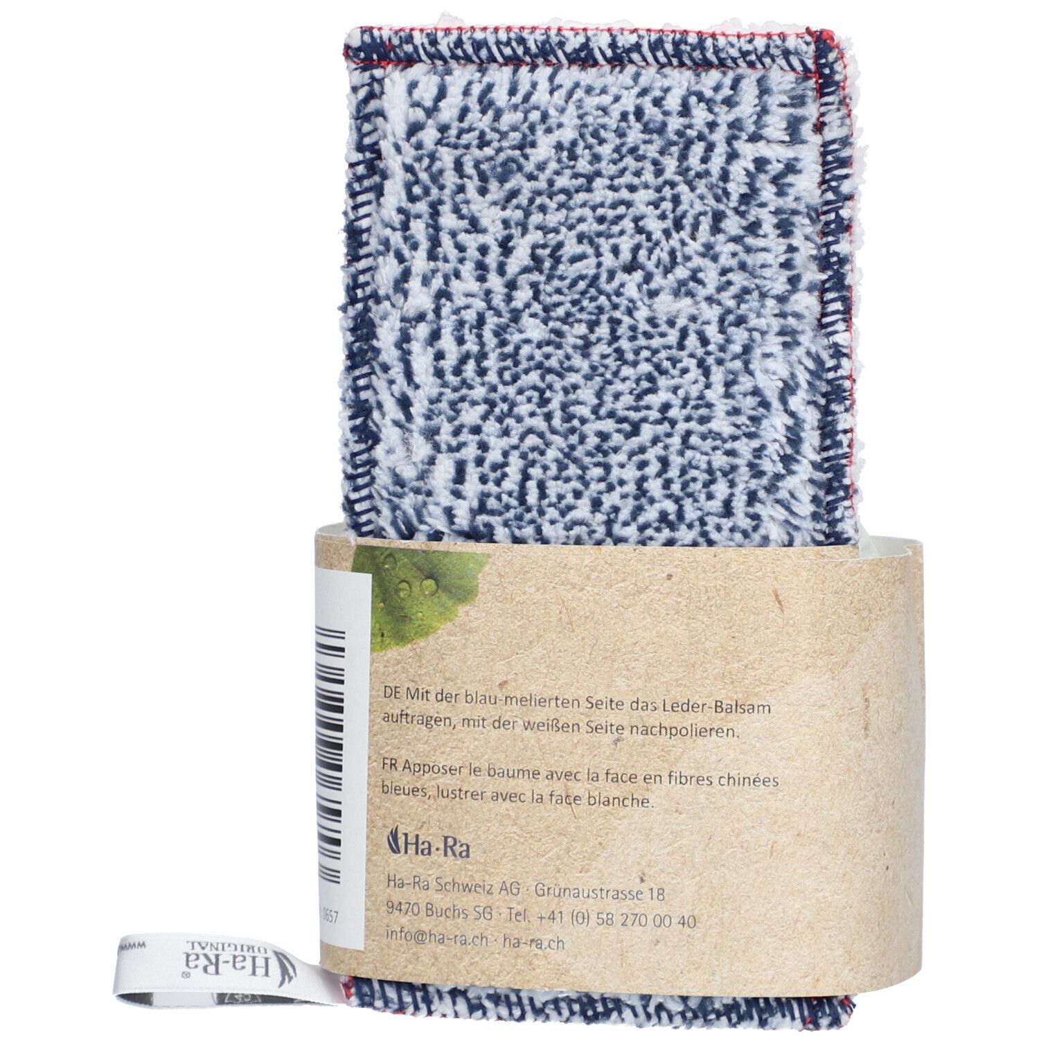 Textil-Pflegetuch mit Lederbalsam-Verpackung. Tuch mit blau-weißem Muster und rotem Rand. Verpackung aus braunem Papier.