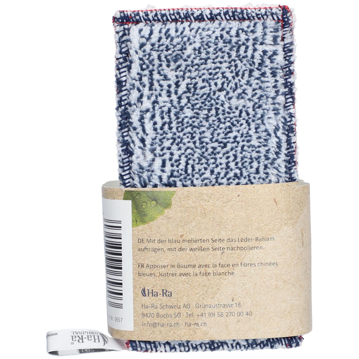 Pflegetuch mit Lederbalsam-Verpackung. Tuch mit blau-weißem Muster und rotem Rand. Verpackung aus braunem Papier. Text auf der Verpackung.