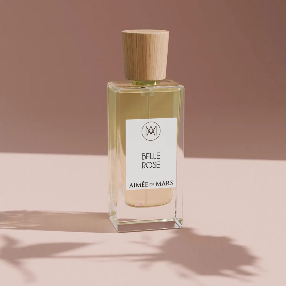 Parfümflasche mit Holzverschluss. Auf dem Etikett: Belle Rose, Aimée de Mars. Rosa Hintergrund.