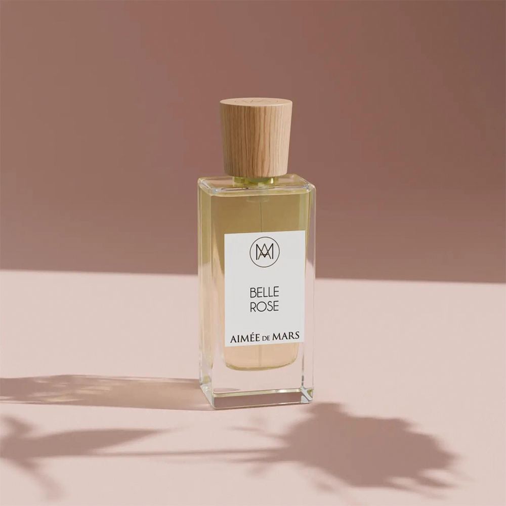 Aimée de Mars Belle Rose Eau de Parfum Flakon. Rechteckige Glasflasche mit Holzverschluss. Auf rosa Hintergrund mit Schatten.