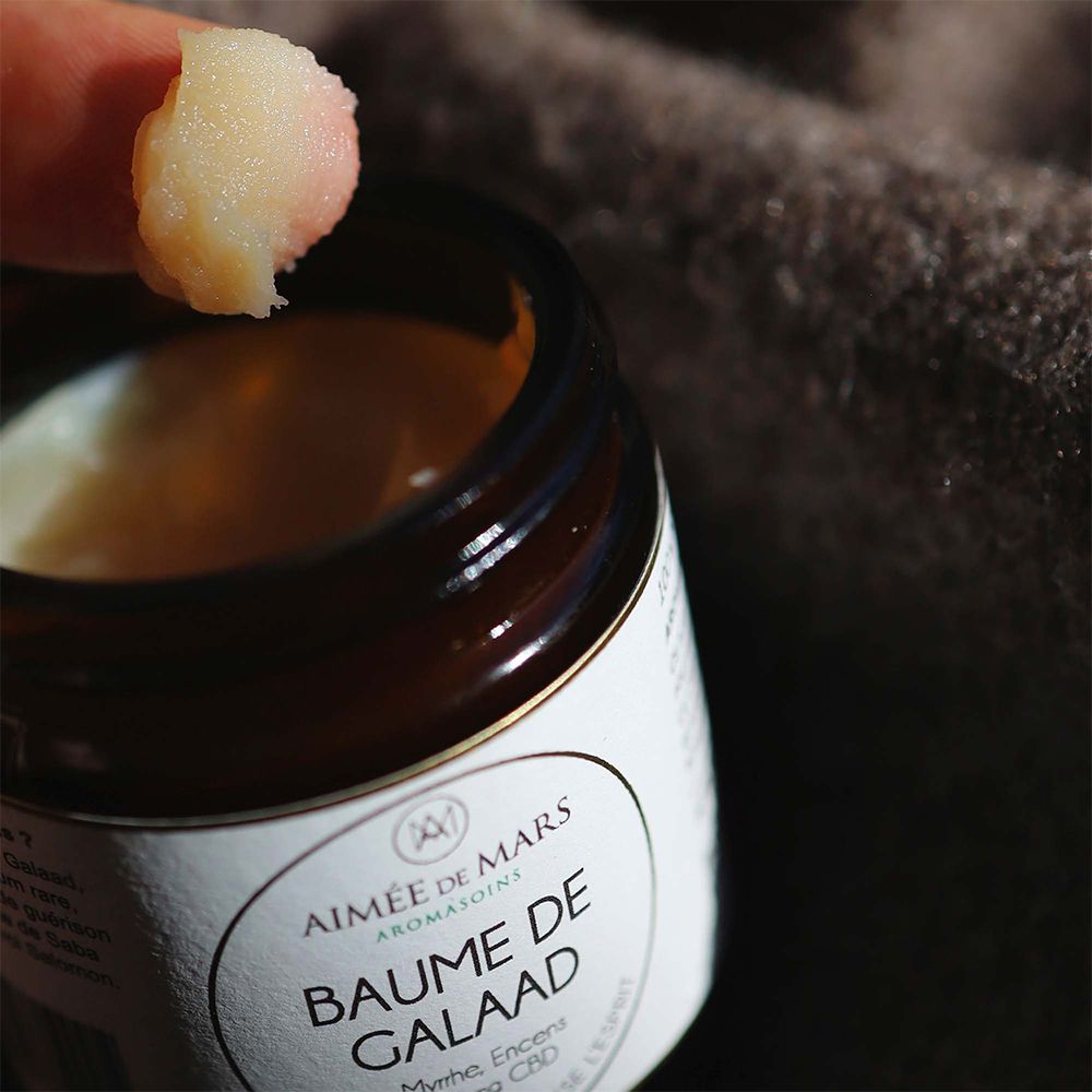 Nahaufnahme eines Fingers mit Balsam. Der Balsam ist hell und cremig. Der Hintergrund ist unscharf.