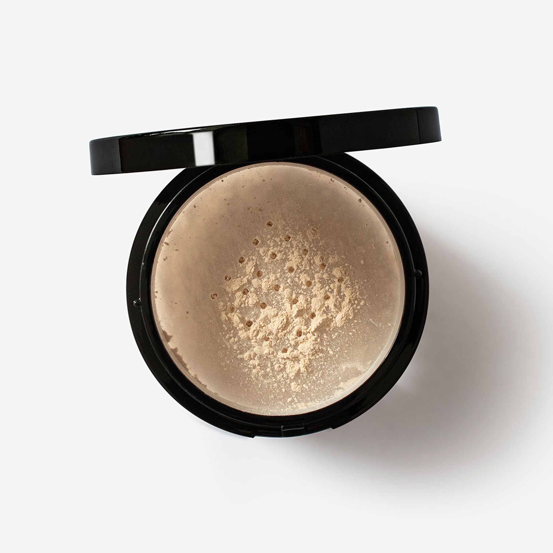 Puder-Dose mit schwarzem Deckel. Puder ist sichtbar. Weißer Hintergrund.