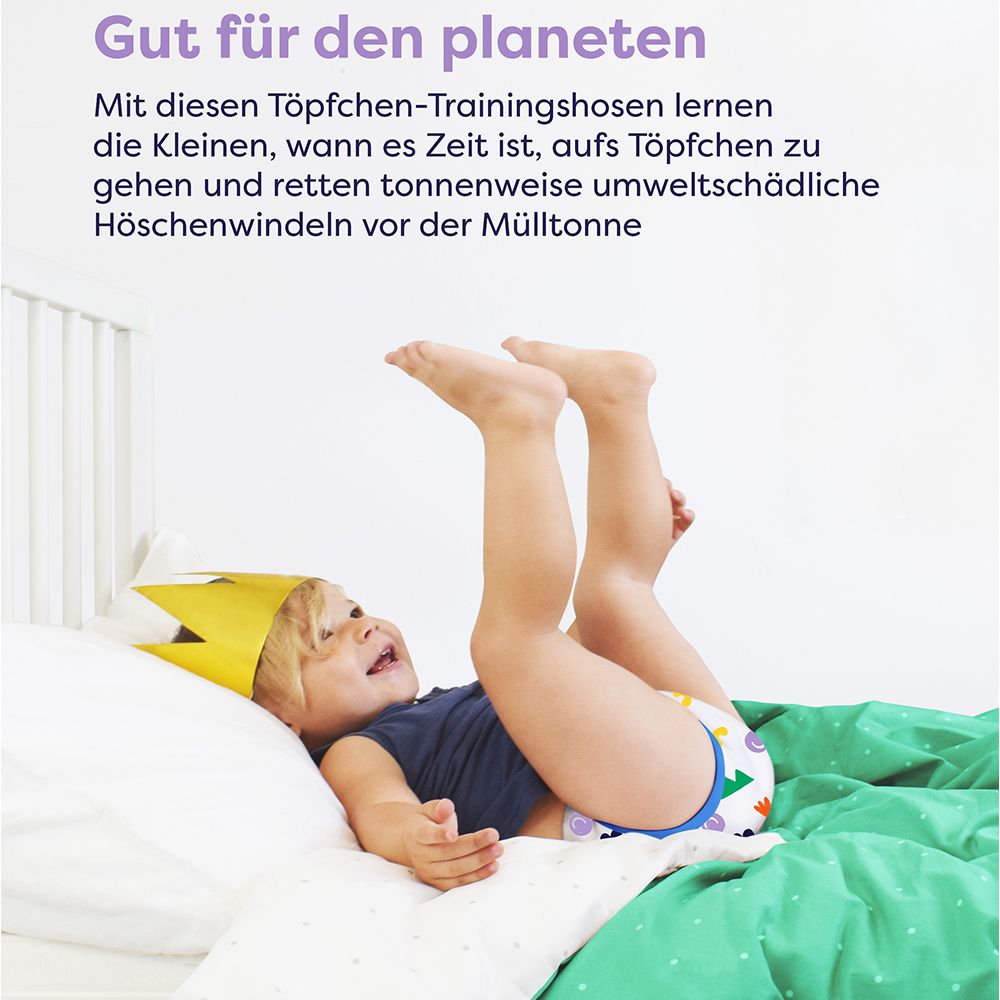 Enfant avec culotte d'apprentissage et couronne sur le lit. Motif : dinosaure. Couverture verte.