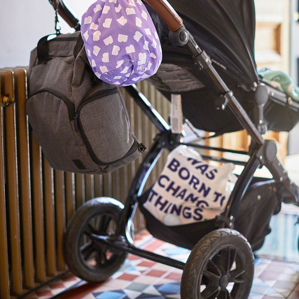 Lila Tasche mit weißem Wolkenmuster, am Kinderwagen befestigt.