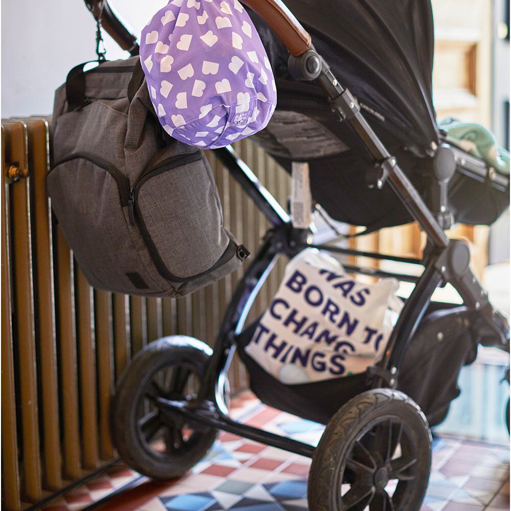 Paarse stoffen tas met wit hartpatroon bevestigd aan een kinderwagen.