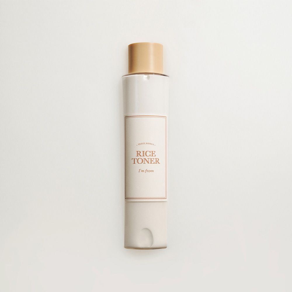 Flasche mit Reis-Toner, beige und weiß, mit goldfarbenem Verschluss.