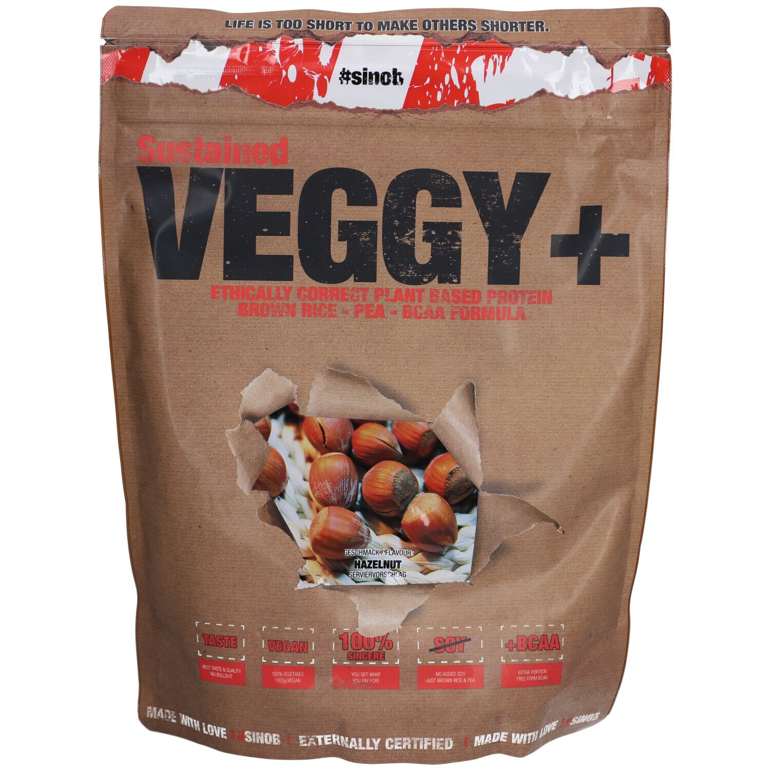Sachet brun "VEGGY+". Trou montrant des noisettes. Texte : "#sinc!", "100%", "+BCAA".