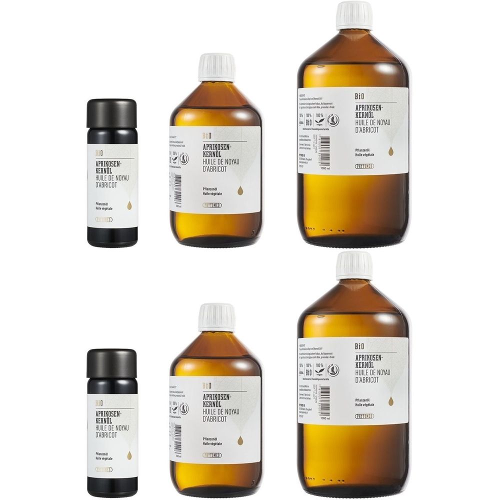 Mehrere Flaschen und kleine Fläschchen mit Etiketten. Aufschrift: Bio Aprikosenkernöl, Flasche mit brauner Flüssigkeit.