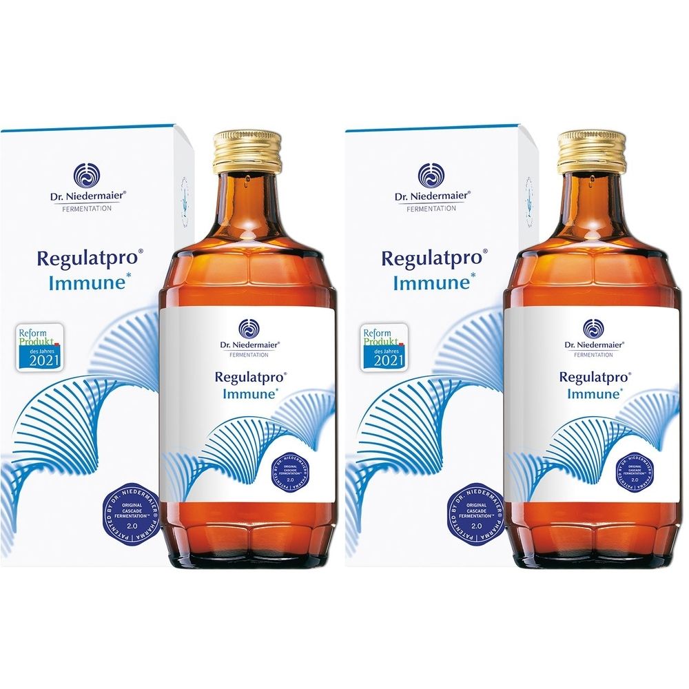 Zwei Flaschen mit brauner Flüssigkeit und goldenem Verschluss, neben zwei weißen Kartons mit Produktaufdruck.