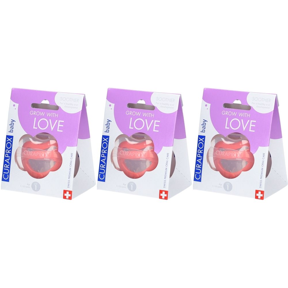 Trois sucettes dans leur emballage. Sucette rose en forme de cœur. Emballage avec l'inscription "GROW WITH LOVE" et "CURAPROX baby".