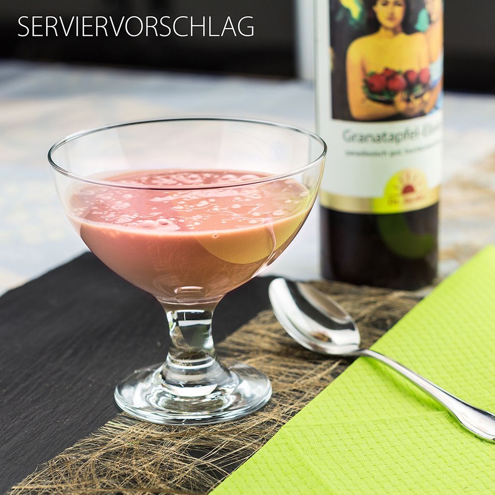 Serviervorschlag: Glas mit rosa Flüssigkeit, Löffel, Flasche im Hintergrund. Auf schwarzem Untergrund.