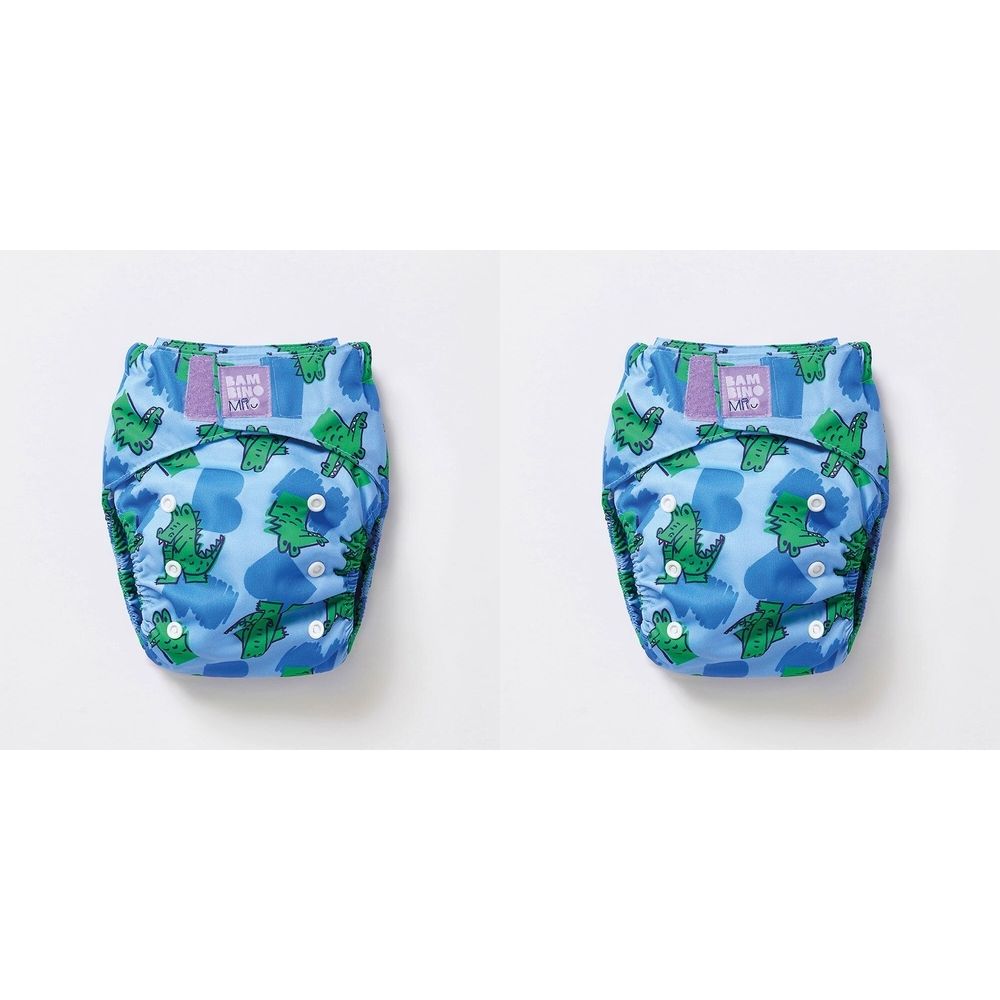 Zwei Stoffwindeln mit Krokodilmuster. Blau mit grünen Krokodilen. Auf jeder Windel ist ein lila Label mit Schriftzug.