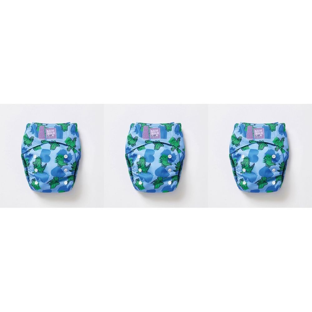 Trois couches lavables bleues avec motif crocodile. Chaque couche a des boutons et un patch violet. Les couches sont posées sur fond blanc.
