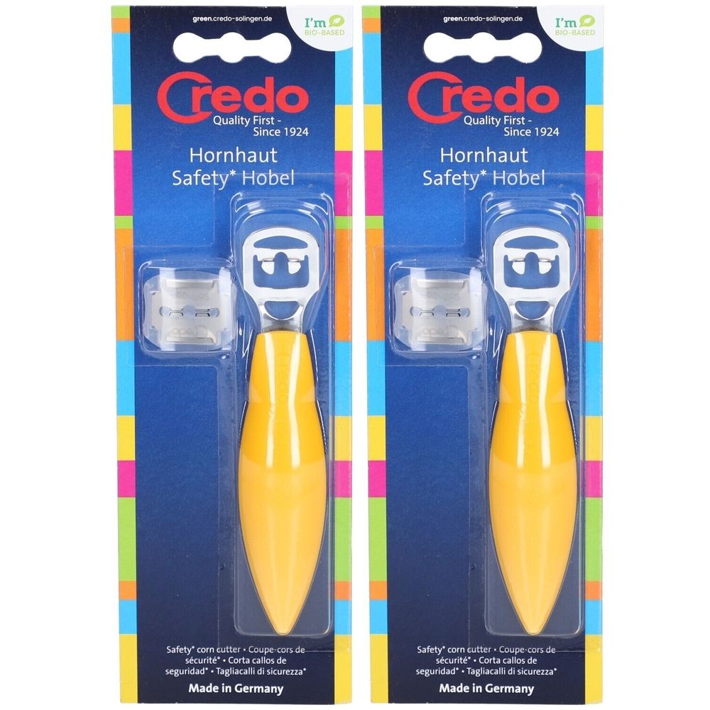 Deux coupe-cors dans un emballage. Manche jaune, lame argentée, capuchon de protection transparent. Marque : Credo.