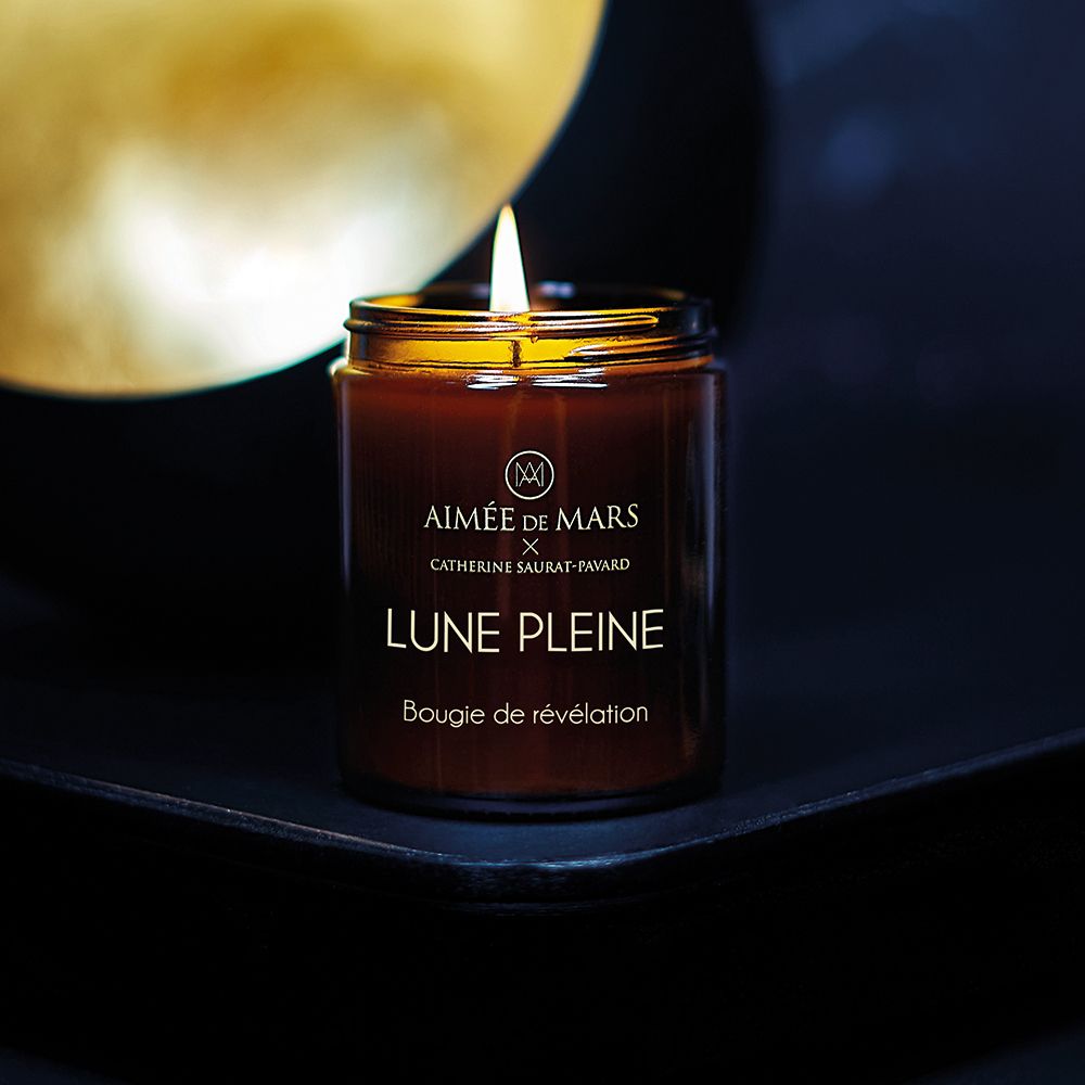 Brennende braune Kerze in Glasbehälter mit schwarzem Deckel. Aufschrift: AIMÉE DE MARS, LUNE PLEINE, Bougie de révélation.