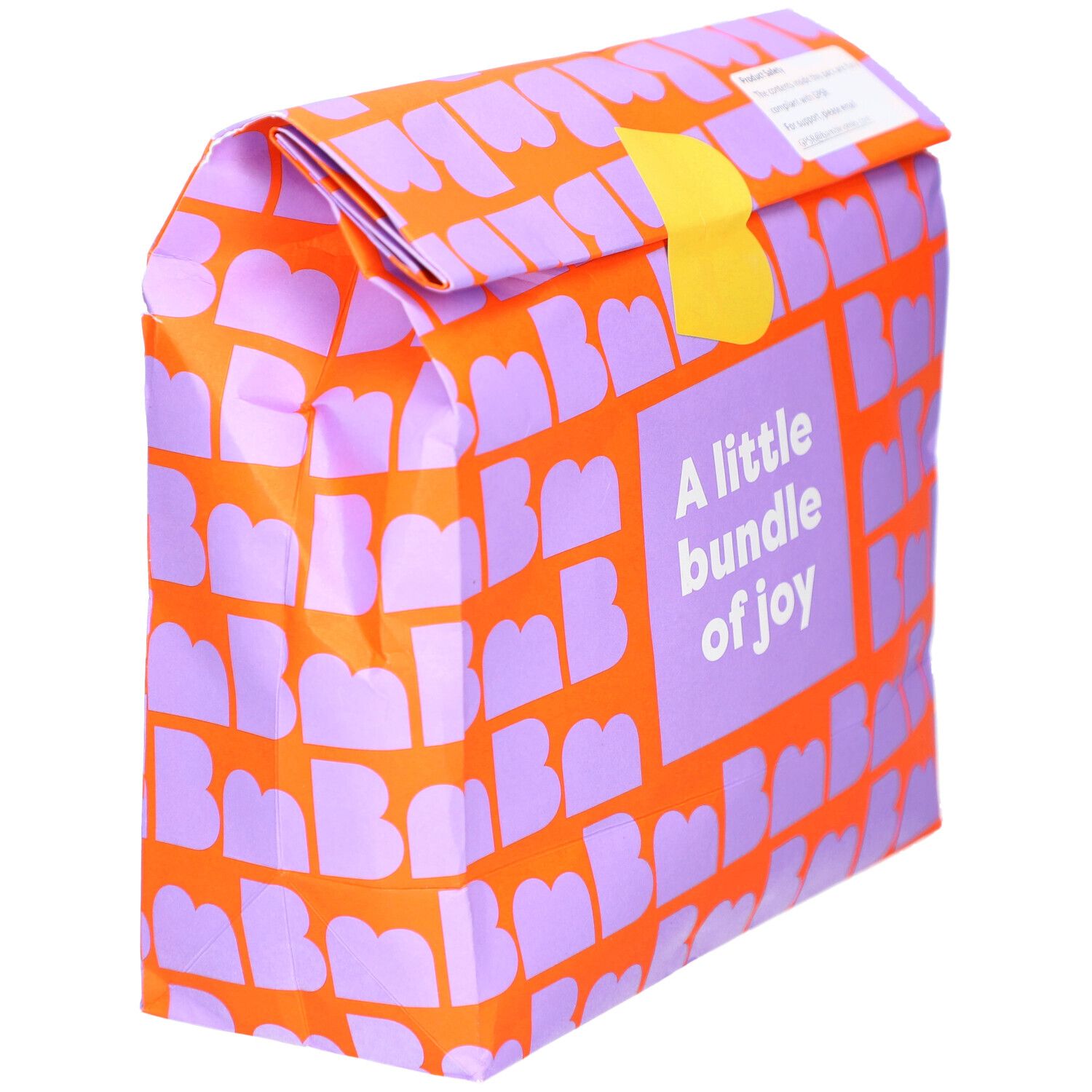 Verpackung mit orangefarbenem Muster und lila Buchstaben. Aufschrift: A little bundle of joy. Gelber Verschluss.