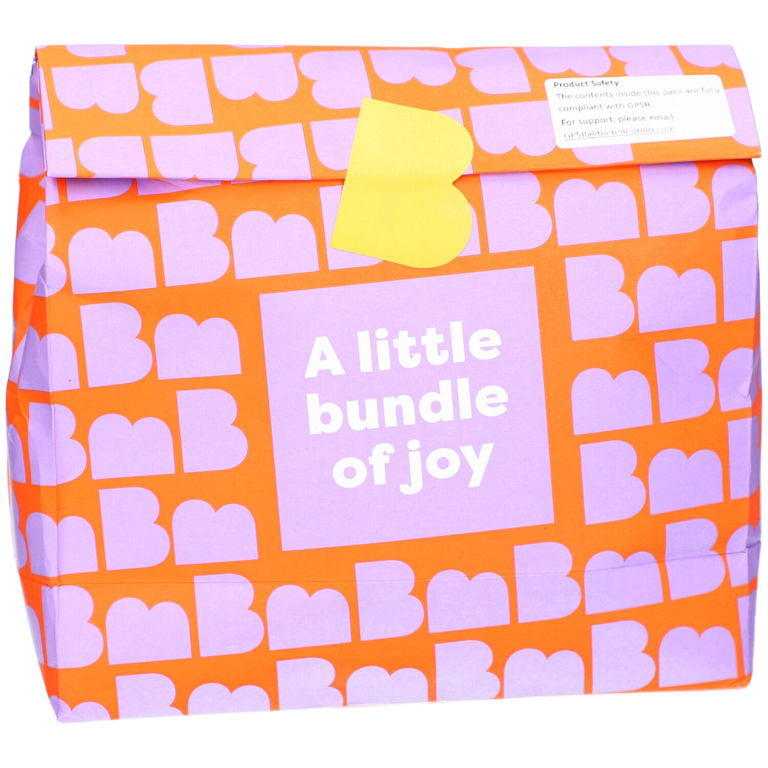 Verpackung mit orangefarbenem Muster und lila Buchstaben. Aufschrift: A little bundle of joy. Gelber Verschluss.
