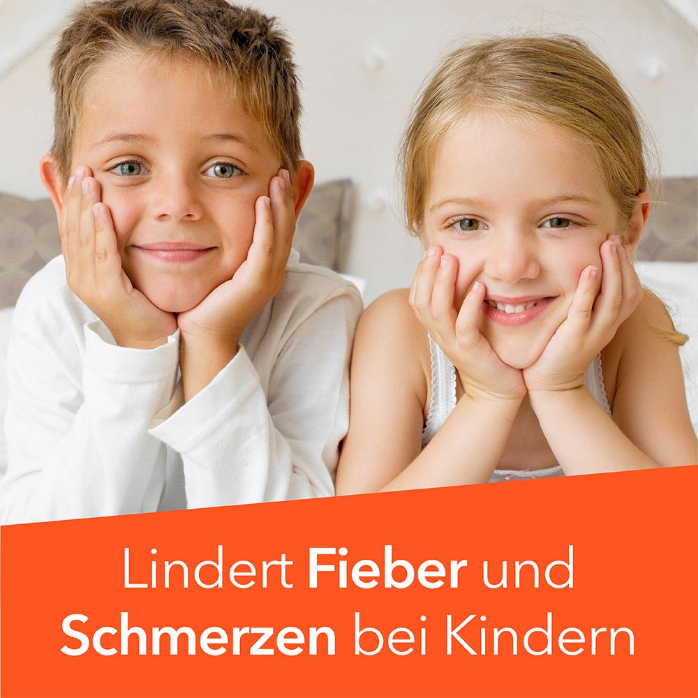 Zwei lächelnde Kinder liegen auf einem Bett, die Wangen in den Händen.