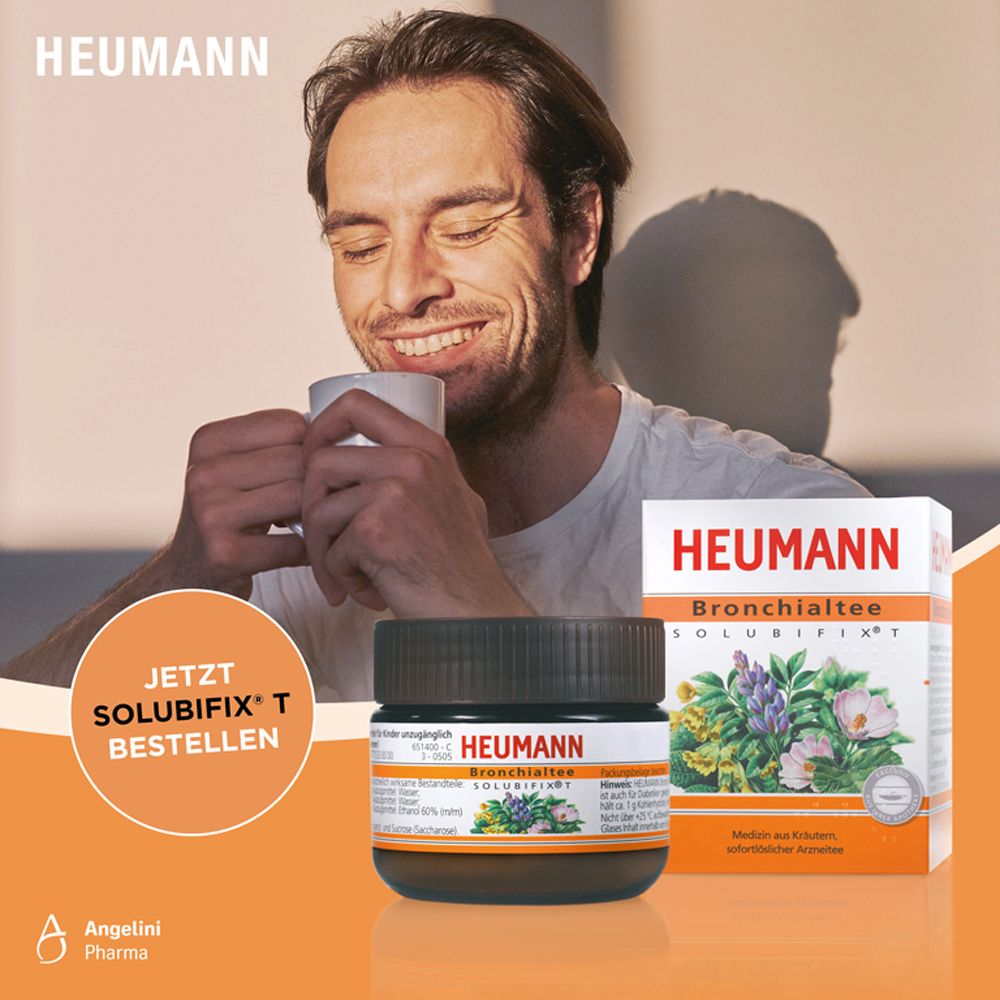 Mann trinkt Tee aus einer Tasse. Daneben eine Dose und eine Schachtel mit Produktinformationen. Aufschrift: Heumann Bronchialtee Solubifix.