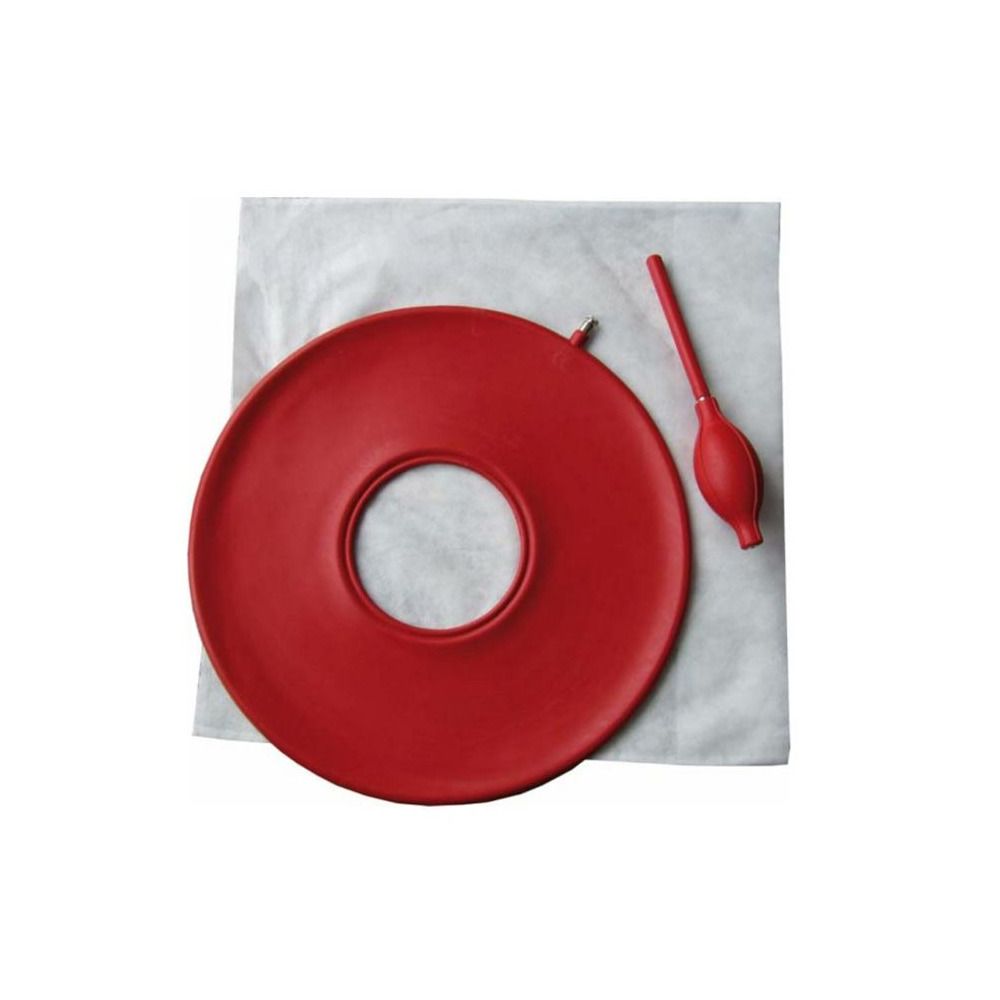 Rotes Gummi-Luftkissen mit Loch, daneben ein roter Blasebalg. Auf weißem Untergrund.