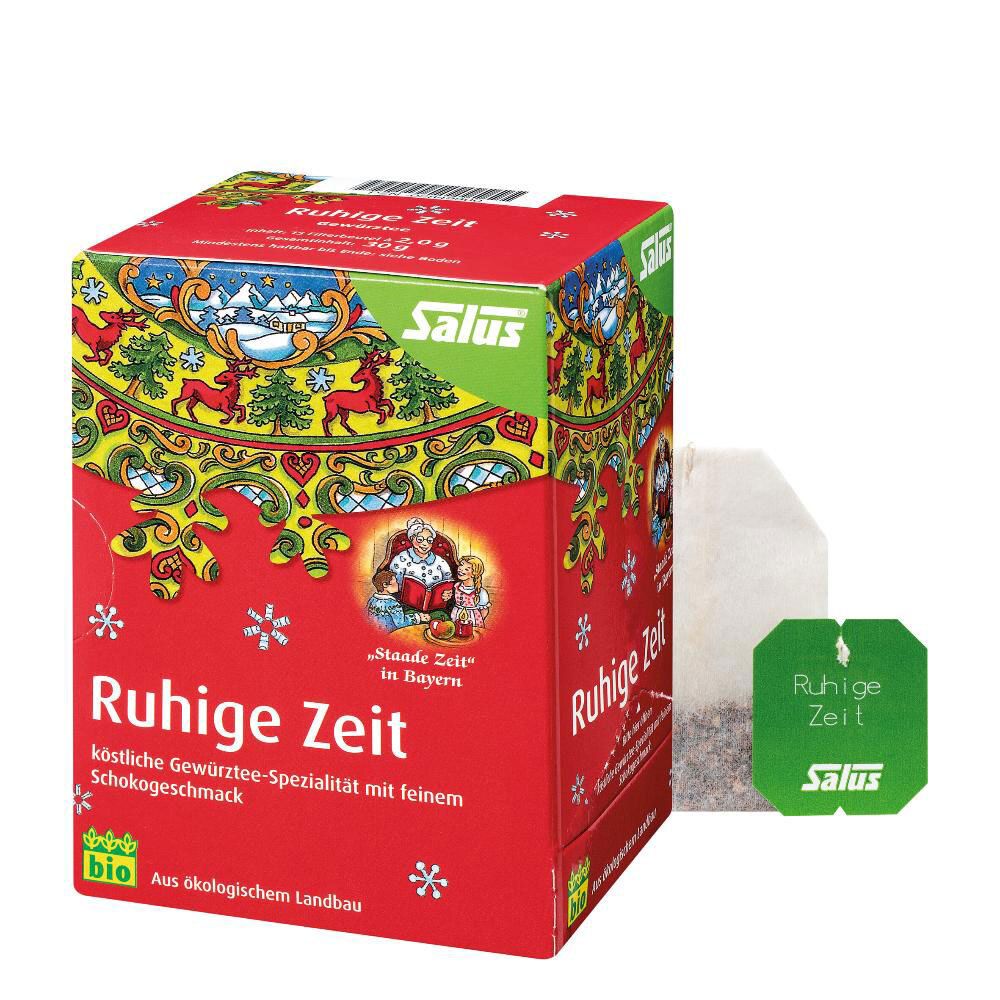 Rote Kartonverpackung mit Salus-Logo und "Ruhige Zeit"-Schriftzug. Ein Teebeutel und ein grüner Teebeutel mit Aufdruck liegen daneben.