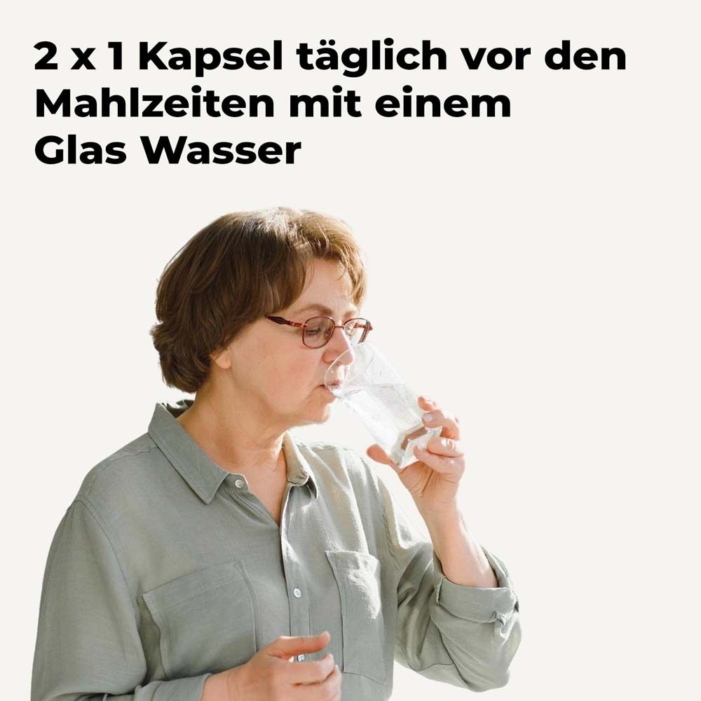Eine Frau trinkt Wasser aus einem Glas. Text: 2 x 1 Kapsel täglich vor den Mahlzeiten mit einem Glas Wasser.