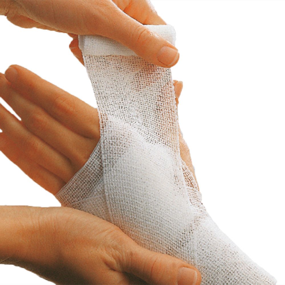 Weißes, elastisches Verbandmaterial wird um eine Hand gewickelt. Die Hand wird von zwei Händen gehalten.